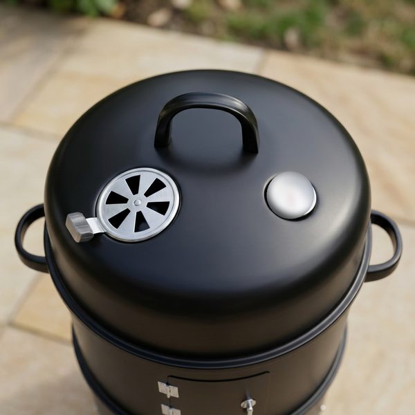 Close-up of the dial thermometer and rotating vent damper on the black smoker lid