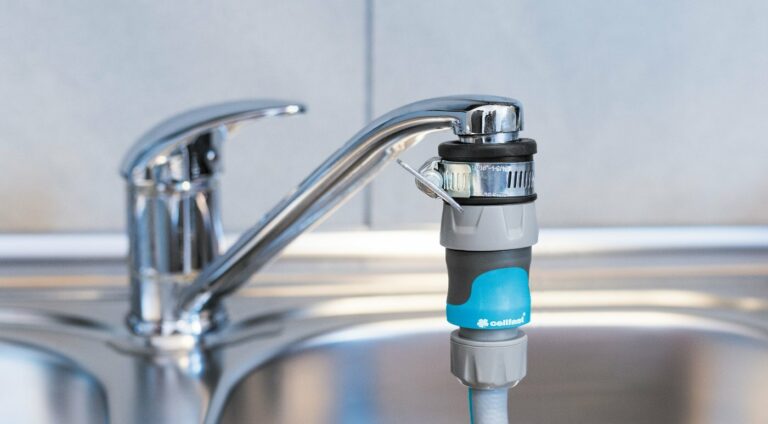 Clamping-ring tap adapter fitted to a kitchen tap, shown connected to a blue hose coupling