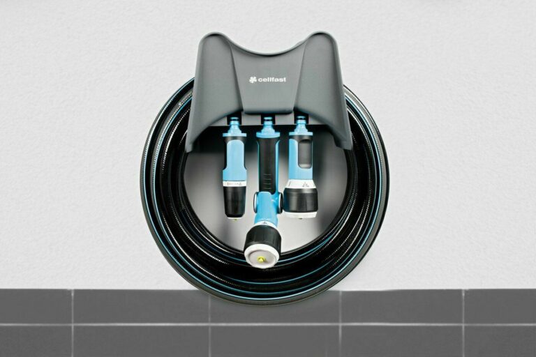 Wall-mounted grey Cellfast hanger shown holding a coiled hose and blue watering accessories